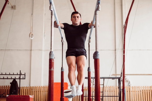 Front view man training on parallel bars