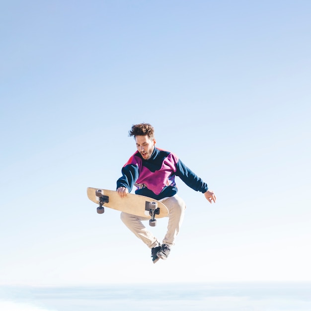 Front view of man with skateboard in air