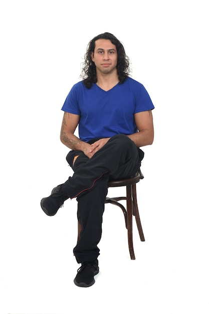 Front view of a man with sportswear sitting on chair looking at camera on white background