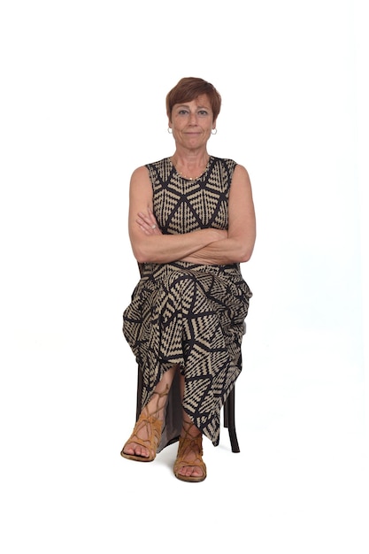 Front view of a middle aged woman sitting on a chair with her legs crossed and arms crossed on white background