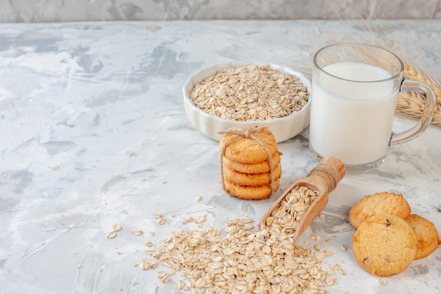 front view milk bottle and milk glass cookies oats bowl on grey background copy place