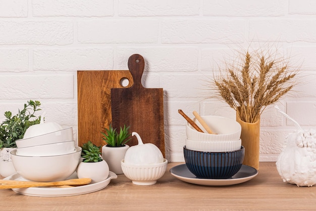 Front view of modern kitchen wooden countertop with set of ceramic bowls and decorative pumpkins Wooden cutting boards Eco style