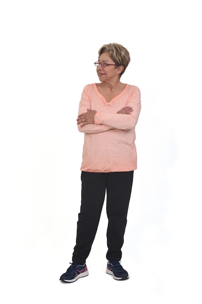 Front view o f a full portrait of happy senior woman with sportswear looking side and arms crossed on white background