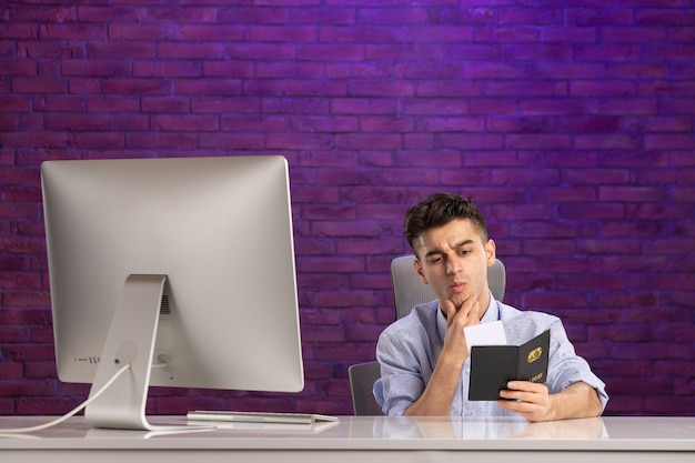 Front view office worker sitting behind his working place with passport and tickets