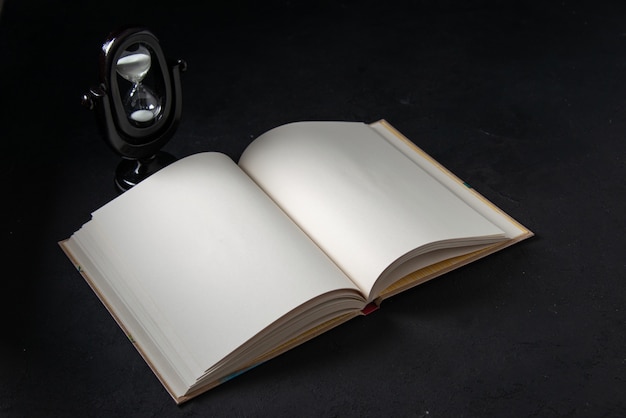 Front view of open book with hourglass on black