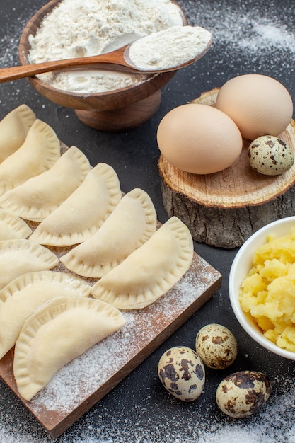 front view raw little hotcakes with flour mushed potatoes and eggs on dark background pie dough cake bake cooking oil biscuit oven