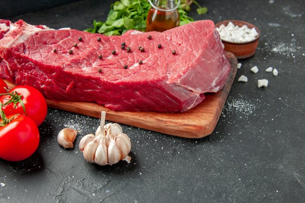 front view raw meat slice with greens and tomatoes on the dark background cooking dish food meat dinner meal butcher barbecue color