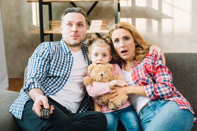 Front view of shocked family watching television in home