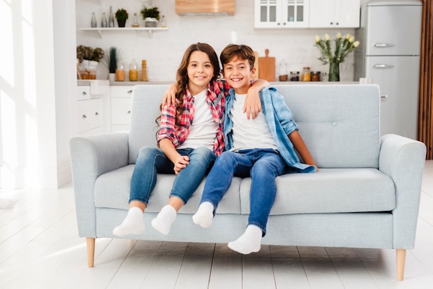 Front view siblings hugging on couch