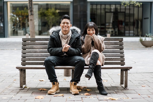 Front view of smiley couple sitting on a bench