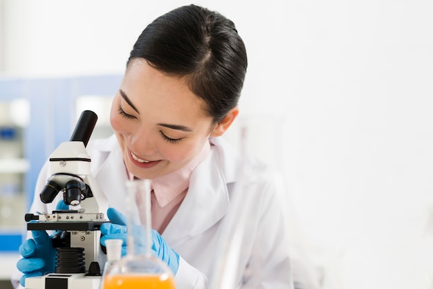 Front view of smiley female scientist and microscope