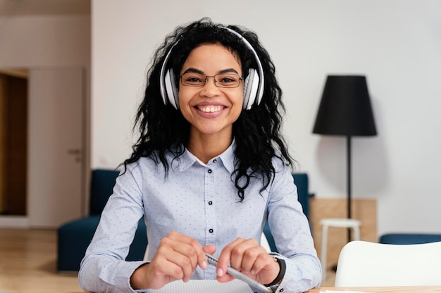 Front view of smiley teenage girl at home during online school with headphones