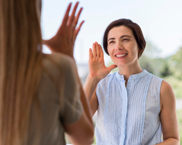 Front view of smiley woman communicating through sign language while outdoors