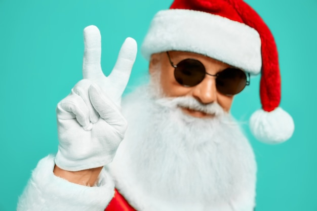 Front view of smiling Santa Claus with long white beard showing peace with two fingers up