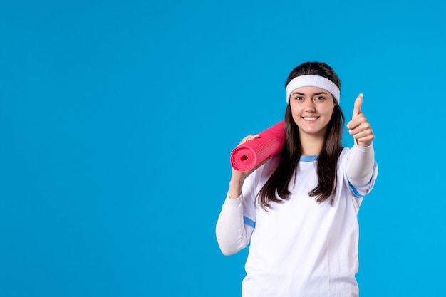 Front view smiling young female with yoga mat