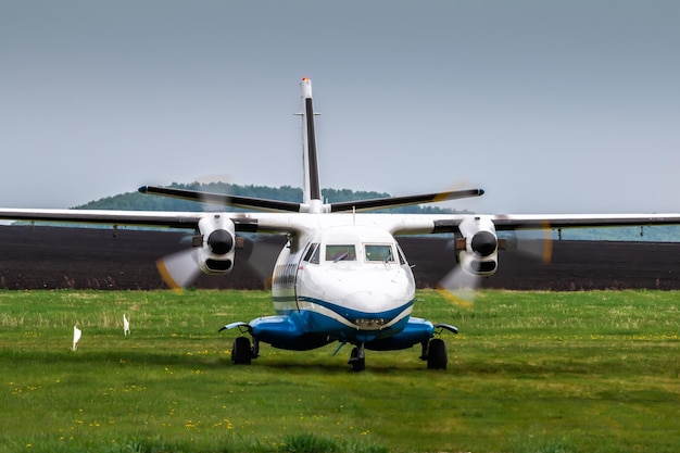 Front view of taxiing a turboprop passenger airplane at a rural airfield in cloudy summer weather