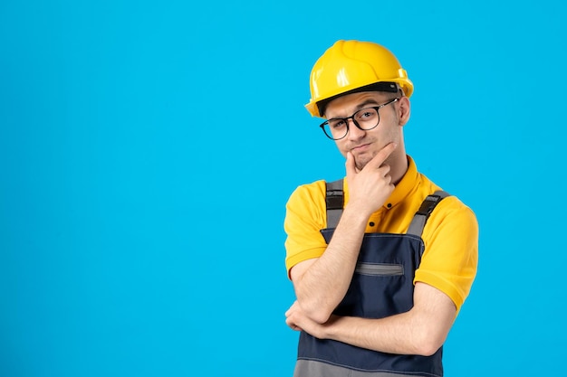 Front view of thinking male builder in uniform on blue 