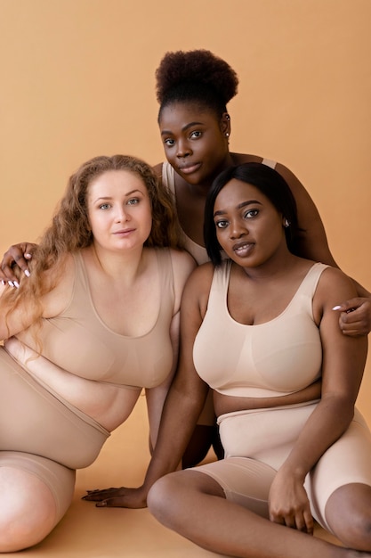 Front view of three women in nude illusion body shapers posing together