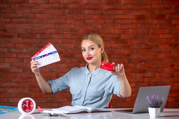 front view of travel agent holding tickets and red credit card assistant global map occupation agency professional manager job money