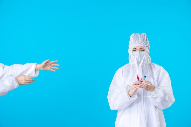 front view two female doctors in protective suit and mask one holding injection on blue background medical covid- virus health hospital pandemic