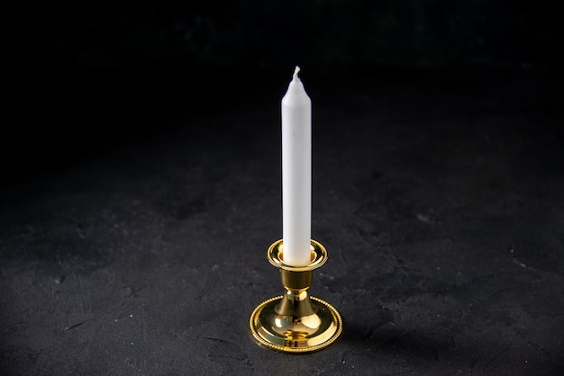 Front view of white candle in golden insert on black