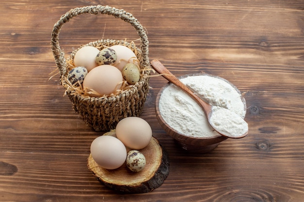 front view white flour with eggs on brown wooden desk meal pie biscuit oven cake bake cooking