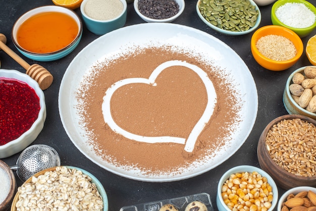 front view white flour with nuts seeds cereals raisins and jelly on a dark background cake breakfast food pie dust bake color cook dough heart