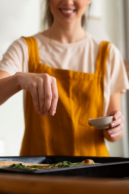 Photo front view woman cooking pizza  in kitchen