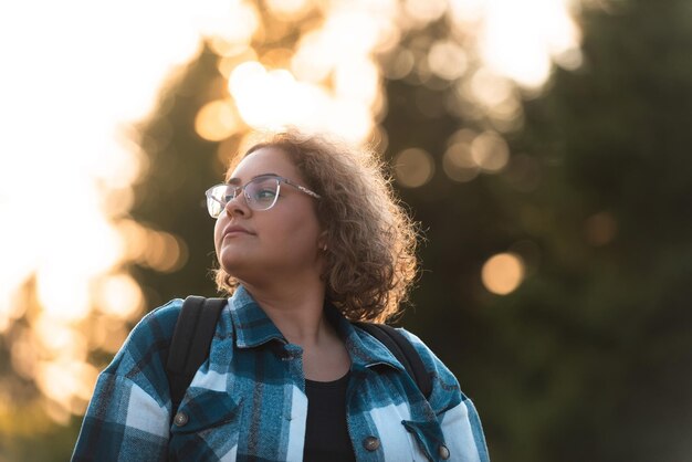 Front view of woman hiker standing outdoors in nature at sunset