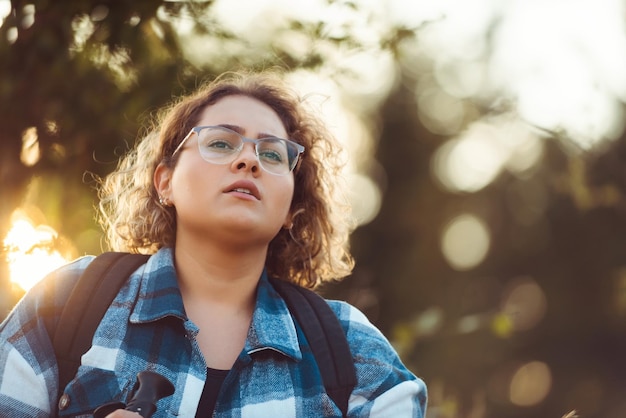 Front view of woman hiker standing outdoors in nature at sunset