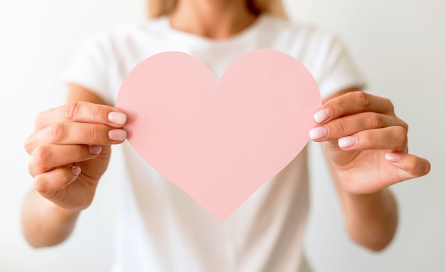 Front view of woman holding paper heart in hands