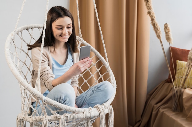 Front view of woman holding smartphone at home