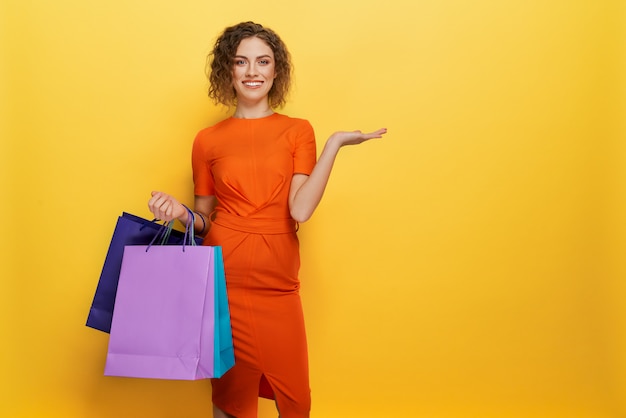 Front view of woman in orange dress keeping paper bags