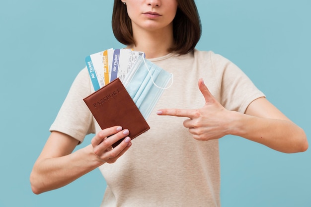 Front view woman pointing to some airplane tickets