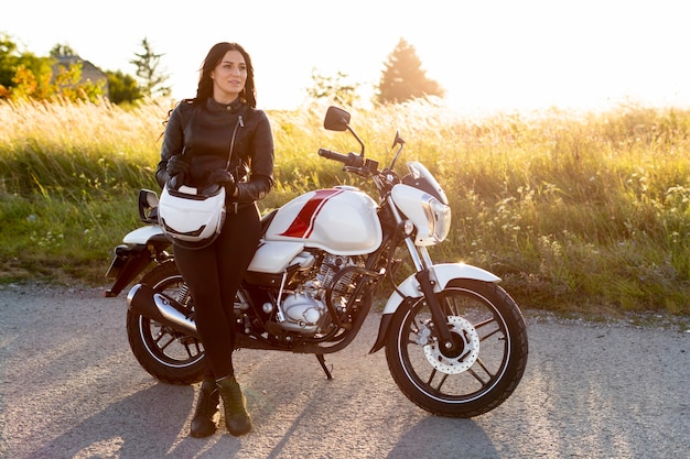 Front view of woman posing next to her motorcycle