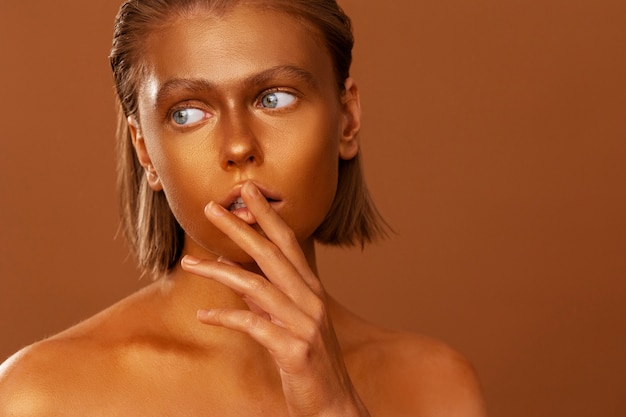 Front view woman posing with gold body painting