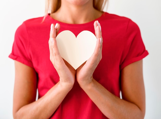 Front view of woman in t-shirt holding paper heart