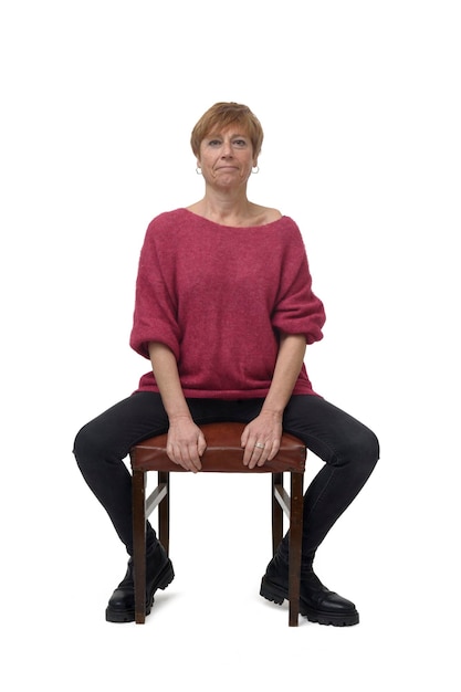 Front view of a woman in tight jean pants sitting on chair looking at camera and open legs on white background