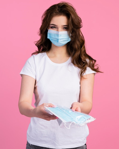 Front view of woman with medical mask offering other masks