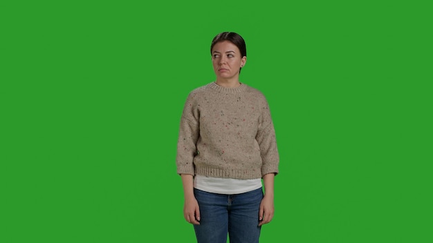 Front view of woman woman showing rejection and pushing something aside, expressing refusal and denial looking displeased. Female model acting discontent moving object, standing over greenscreen.