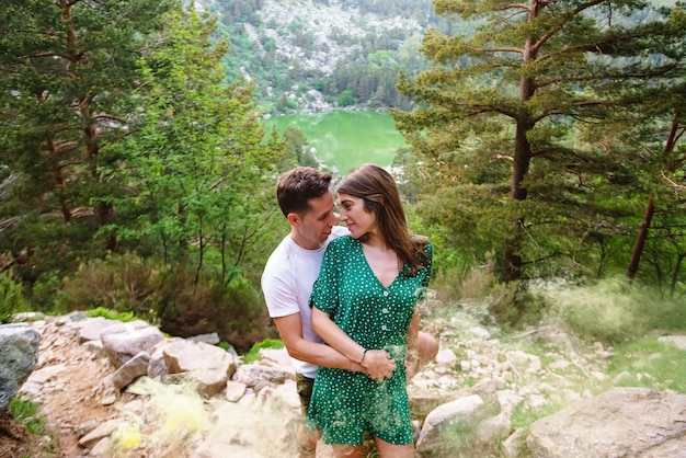 Front view of young couple in love hugging in the mountain surrounded by nature and green fog. Horizontal view of couple traveling in the black lagoon in Soria . People and travel in Spain concept.