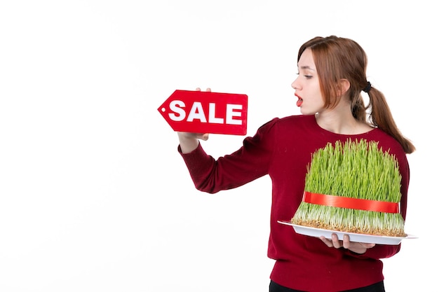 front view young female holding big novruz semeni and sale nameplate on white background concept ethnicity family shopping performer ethnic spring colour