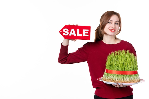 front view young female holding big novruz semeni and sale nameplate on white background concept ethnicity family shopping performer ethnic spring colours