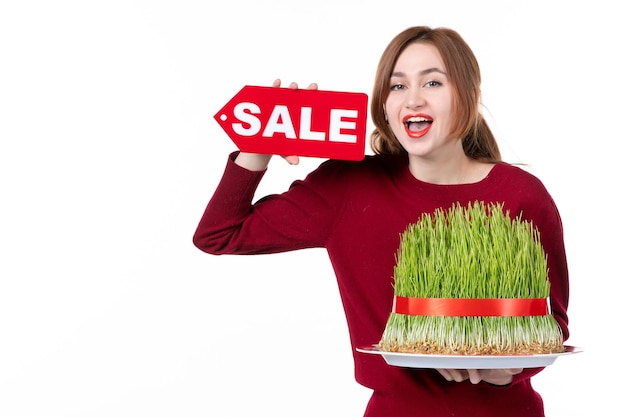 front view young female holding big novruz semeni and sale nameplate on white background spring colours ethnicity shopping family ethnic performer