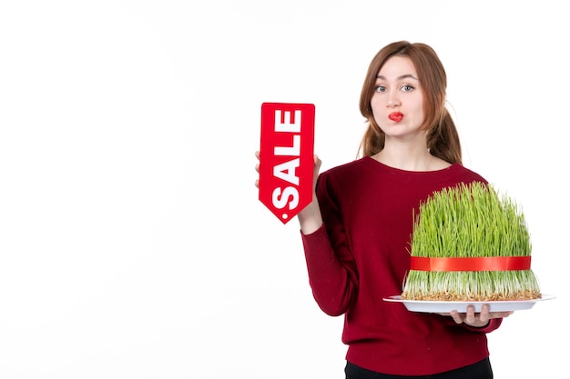 front view young female holding big novruz semeni and sale nameplate on white background spring performer concept ethnicity shopping ethnic colour family