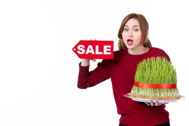 front view young female holding big novruz semeni and sale nameplate on white background spring performer concept ethnicity shopping ethnic colours family