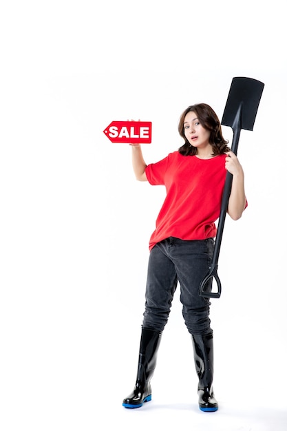 front view young female holding black shovel and red sale writing on white background work soil cemetery job digging emotion