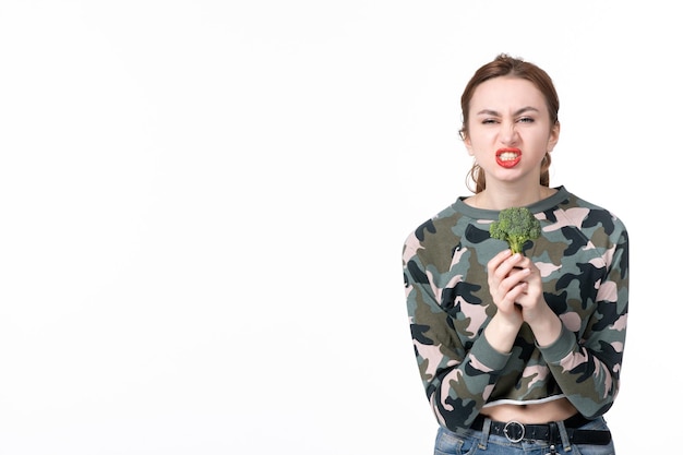 Front view young female holding little green broccoli on white background lunch meal salad dish food human diet healthcare