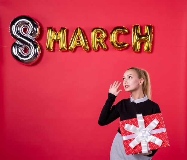 front view young female holding present with march decoration on red background passion salon womans day feminine money luxurious shopping