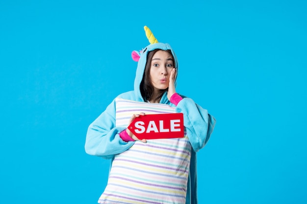 front view young female in pajama party holding sale writing and pillow on blue background nightmare bed dream sleep late night friends fun color